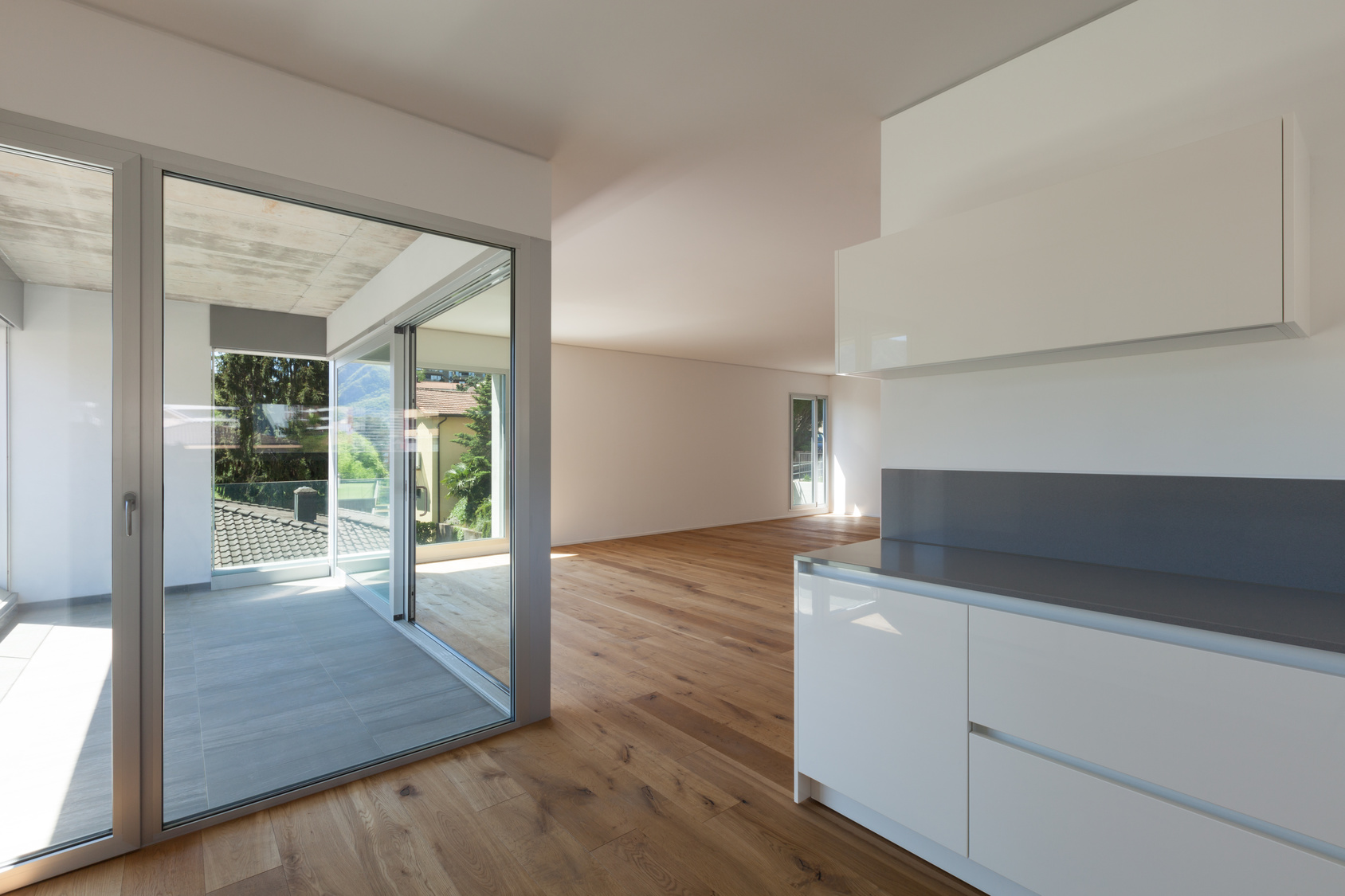 Moderner Wohnbereich mit offener Küche, Schiebetür zum Balkon und Eichenparkett.